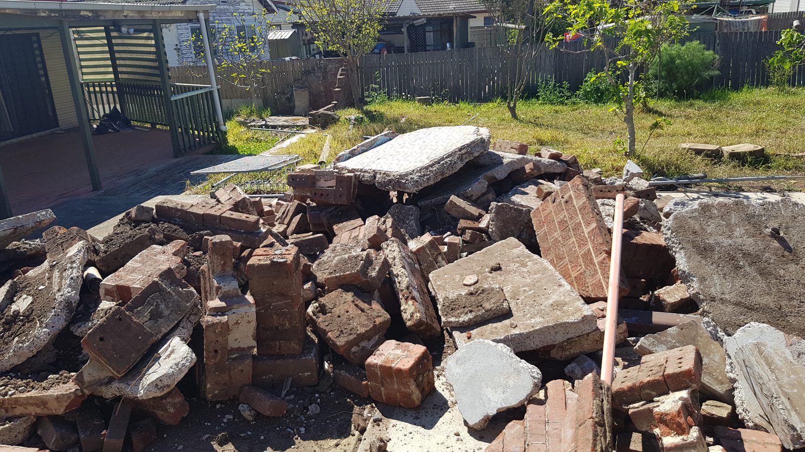Broken bricks, concrete and rubble piled in a backyard