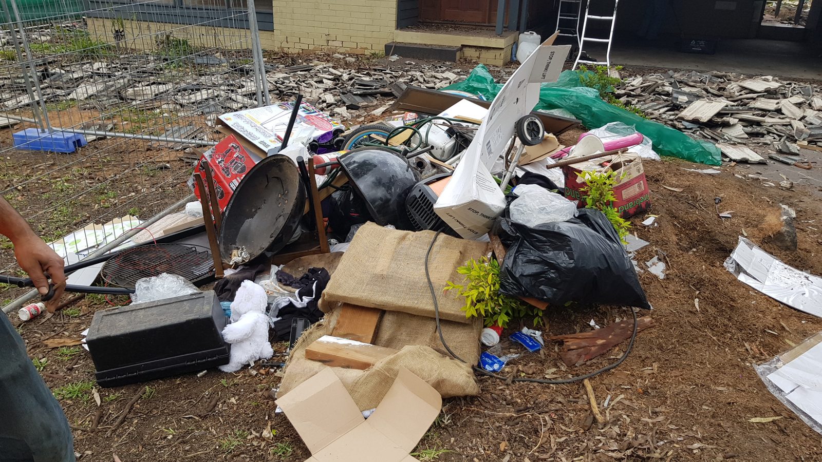 A pile of mixed household rubbish including bags, cardboard, furniture and containers waiting to be sorted