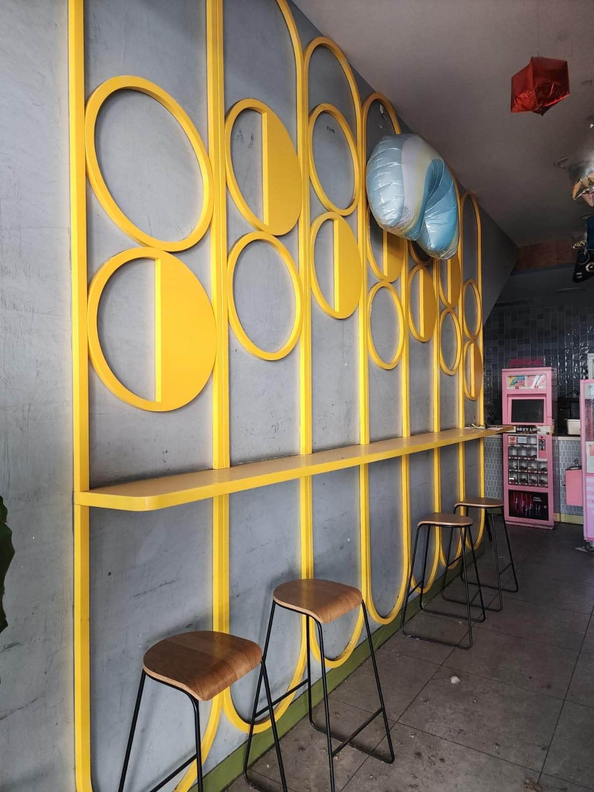 A retail shop fit out with a yellow feature wall, bench and stools before strip out